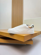 White leather low-top sneakers with lace-up design and cushioned collar