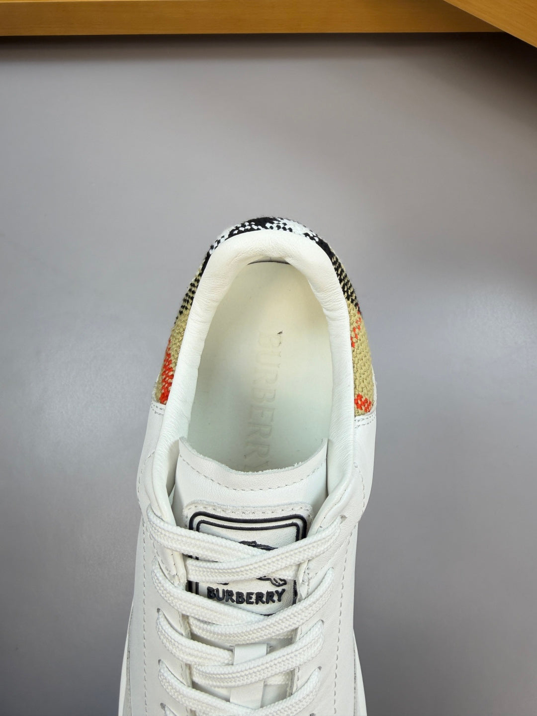 White sneaker heel with check trim and Burberry logo strap