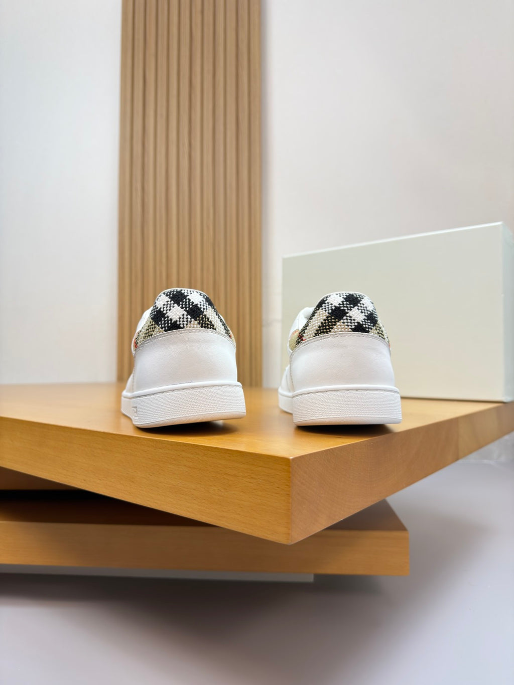 Pair of white sneakers with check-pattern heel tabs on the back