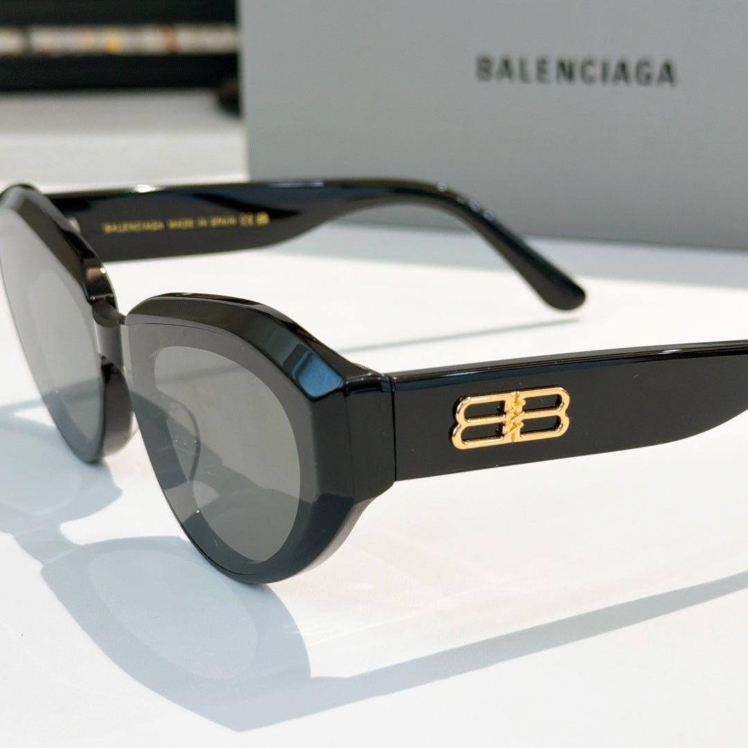Balenciaga sunglasses, black frames close-up with gold B logo on temple