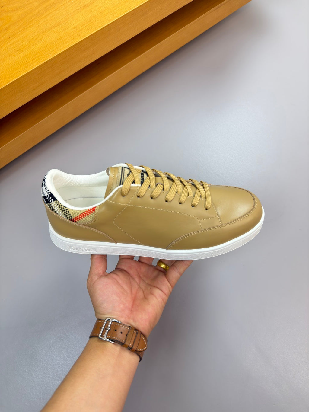 Burberry light tan sneaker held up, lace-up front and patterned collar detail