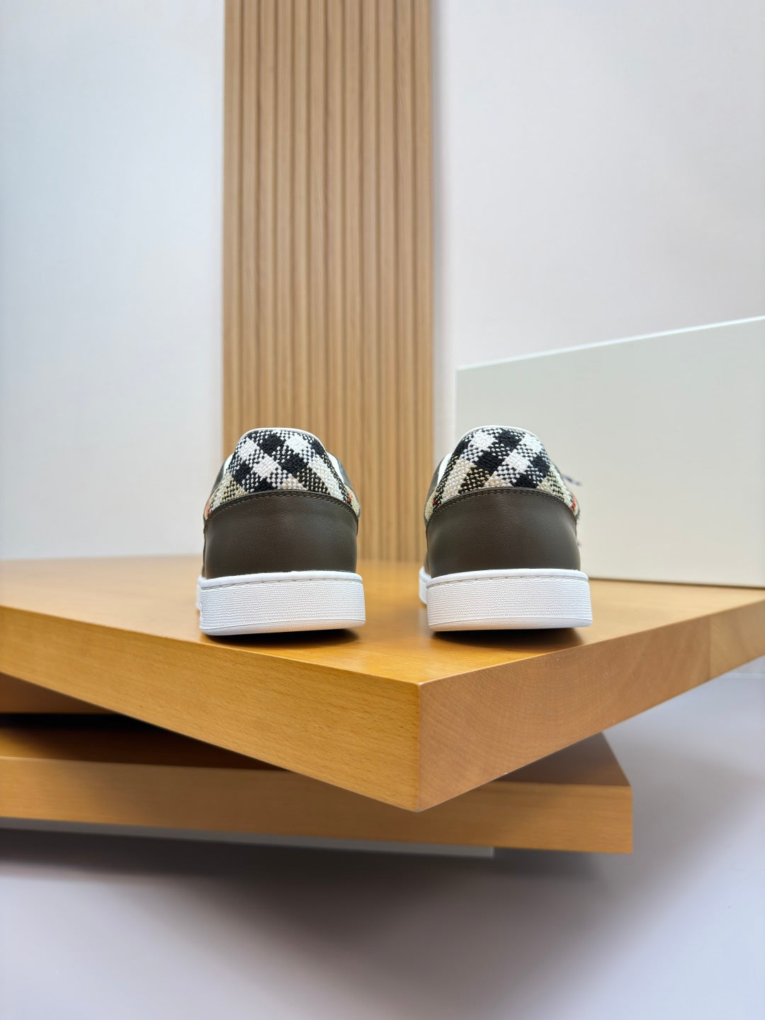 Burberry sneaker heel view pair, dark olive leather with white soles and patterned collar