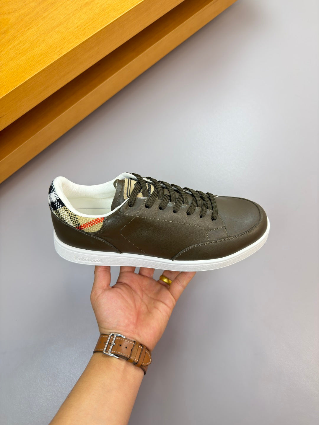 Burberry leather low-top sneaker held up, dark olive with contrast lining and white sole