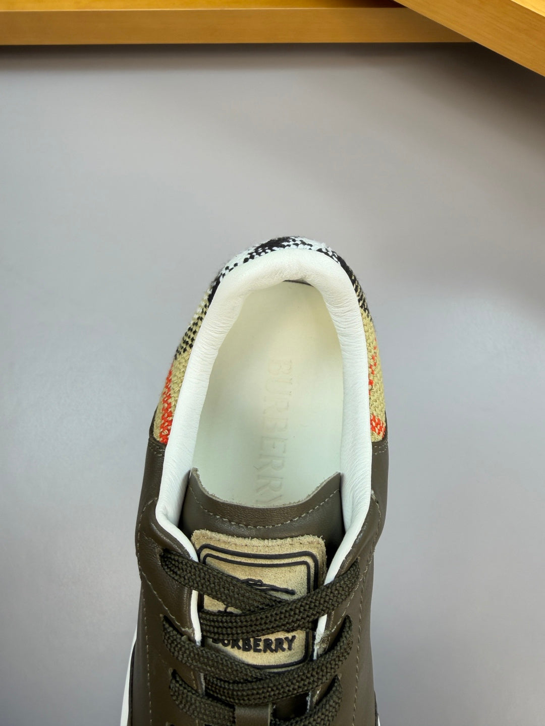 Burberry sneaker tongue and logo area, dark olive leather with lace-up and striped lining
