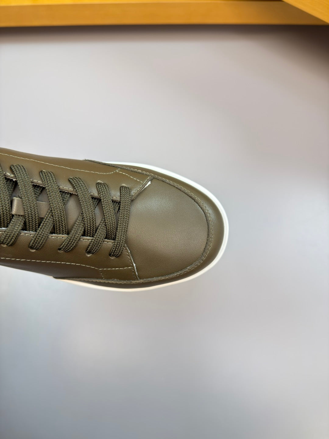 Burberry sneaker toe view in dark olive leather with textured laces and white rubber edge