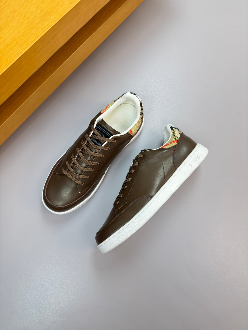 Dark brown low-top sneakers with lace-up closure and white rubber sole