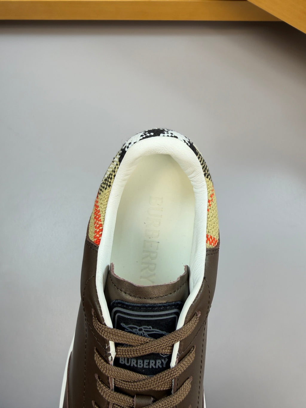 Front view of dark brown sneaker showing 'BURBERRY' on tongue and patterned collar