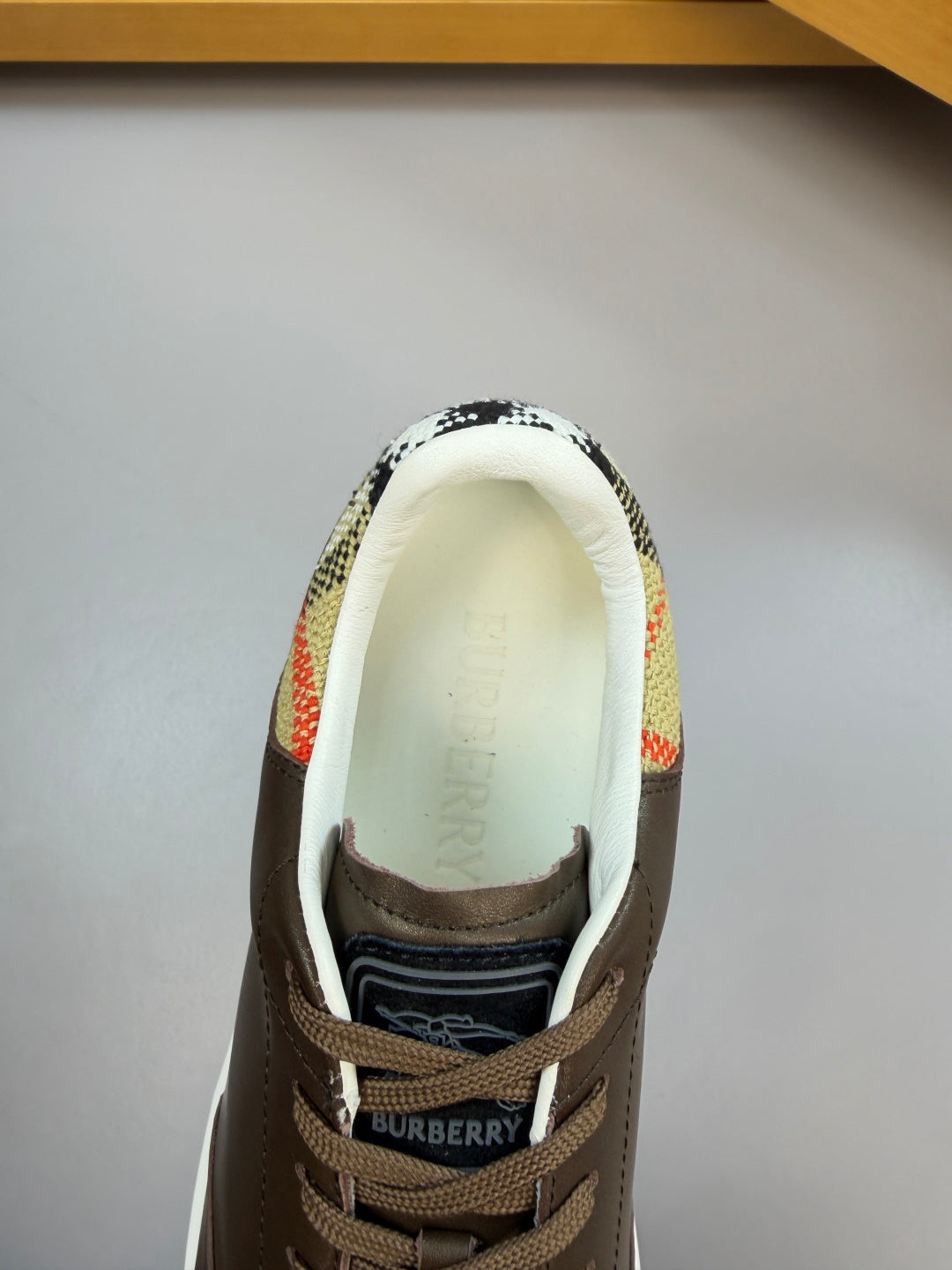 Front view of dark brown sneaker showing 'BURBERRY' on tongue and patterned collar