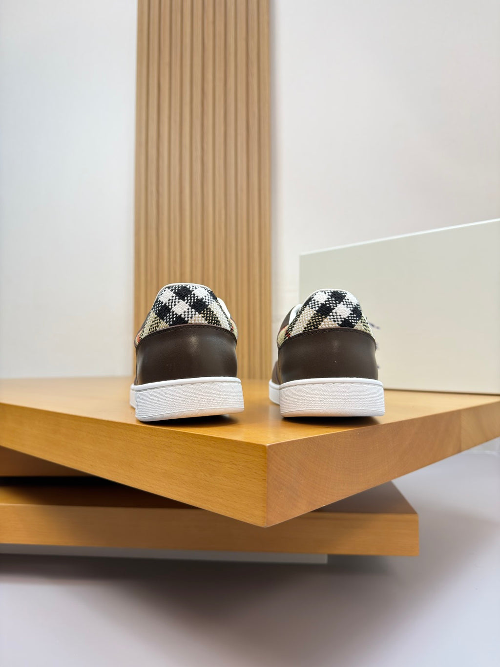 Back view of dark brown sneakers with white soles and check-pattern heel panel