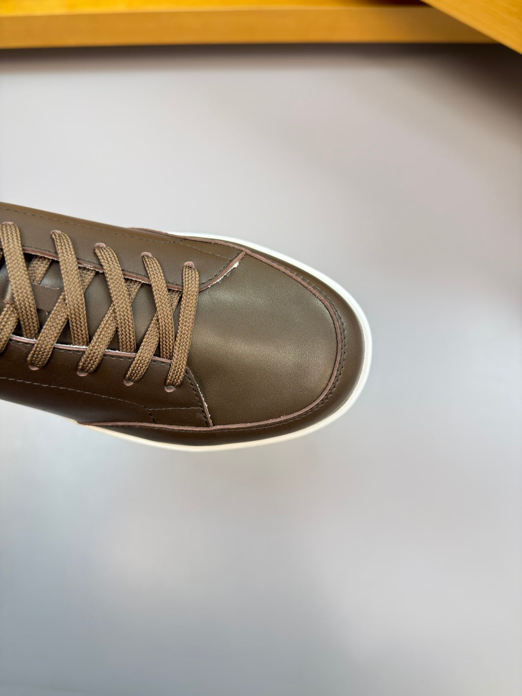 Close-up of dark brown sneaker with lace-up eyelets and white edge sole
