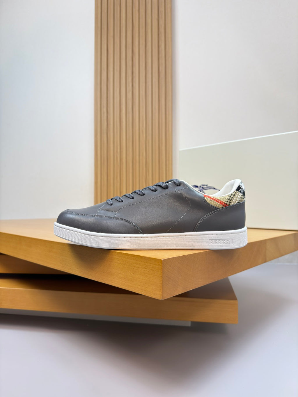 Dark navy lace-up sneakers on a wooden shelf, side profile view