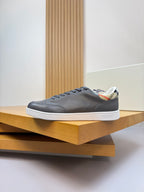 Dark navy lace-up sneakers on a wooden shelf, side profile view