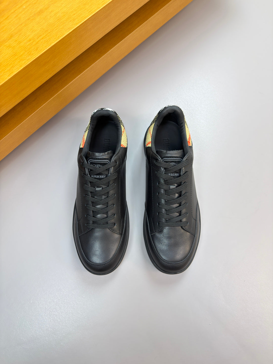 Burberry black leather lace-up sneakers, side view with textured stitching and sole