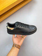 Burberry black leather sneaker held by hand, lace-up with multicolor collar detail