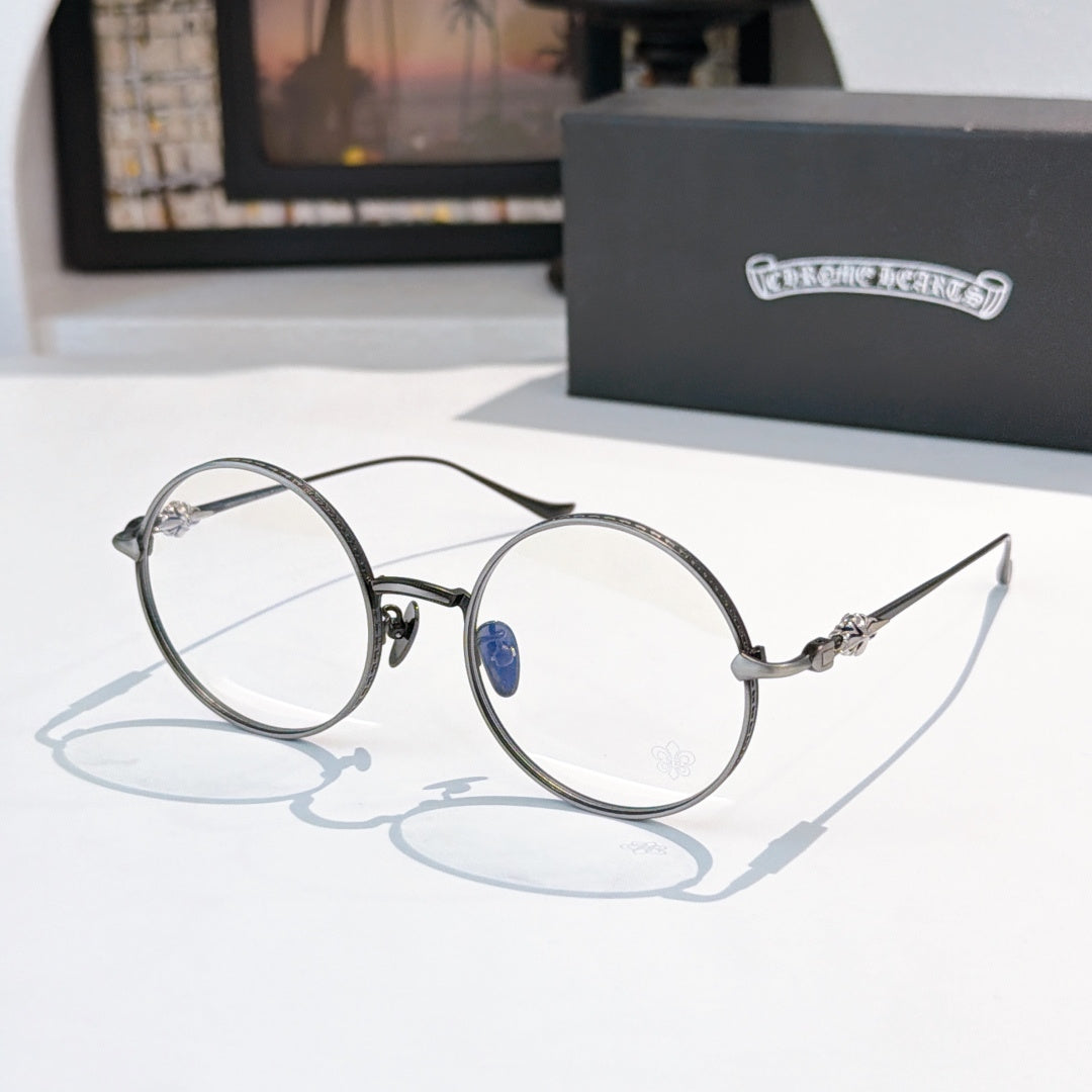 Chrome round eyeglasses with blue center emblem, slim metal frame and clear lenses.