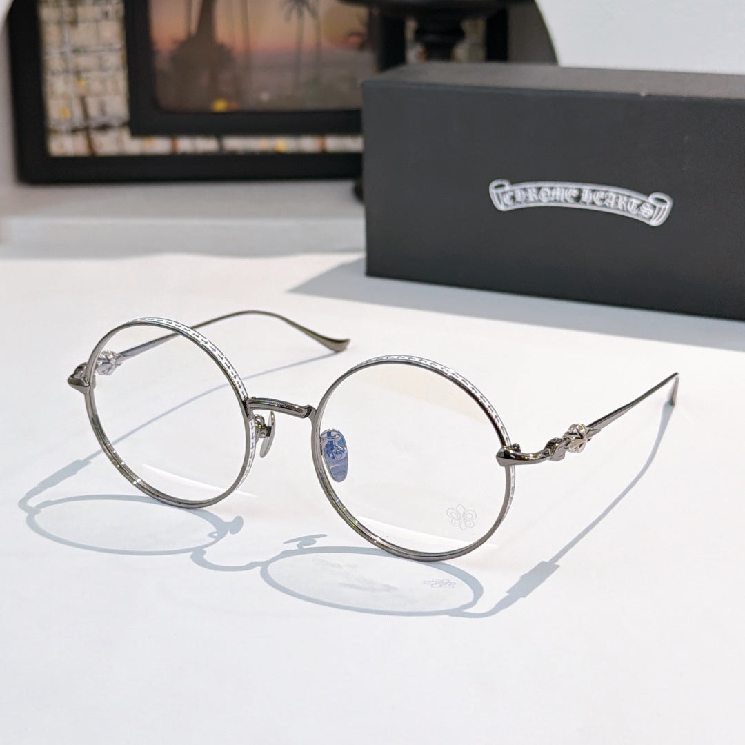 Silver round eyeglasses with blue bridge emblem and decorative metal temple arms.