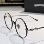 Round eyeglasses with dark metal rim, blue nose pad detail, flower decor on temple.