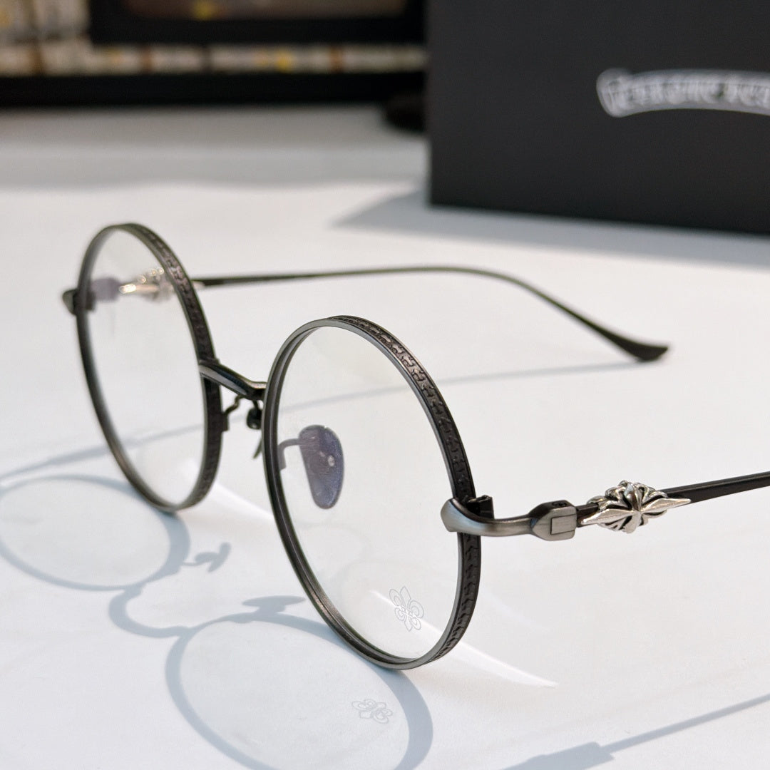 Round eyeglasses with dark metal rim, blue nose pad detail, flower decor on temple.