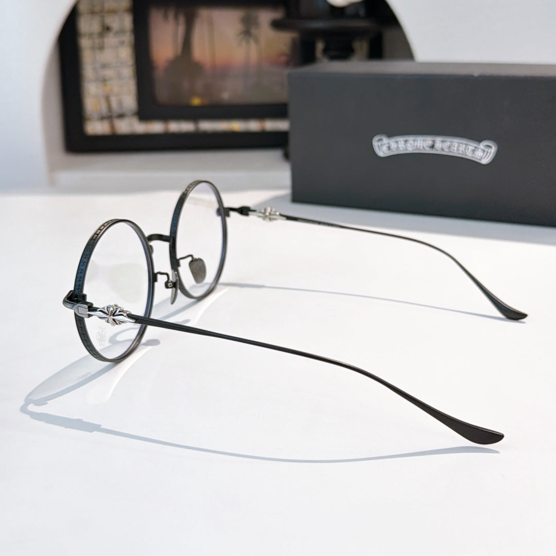 Round eyeglasses with dark metal frame, decorative temple link, clear lenses.