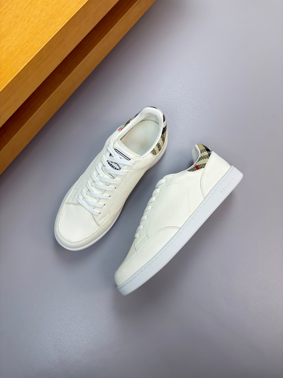 Burberry white lace-up sneakers on display, angled side view