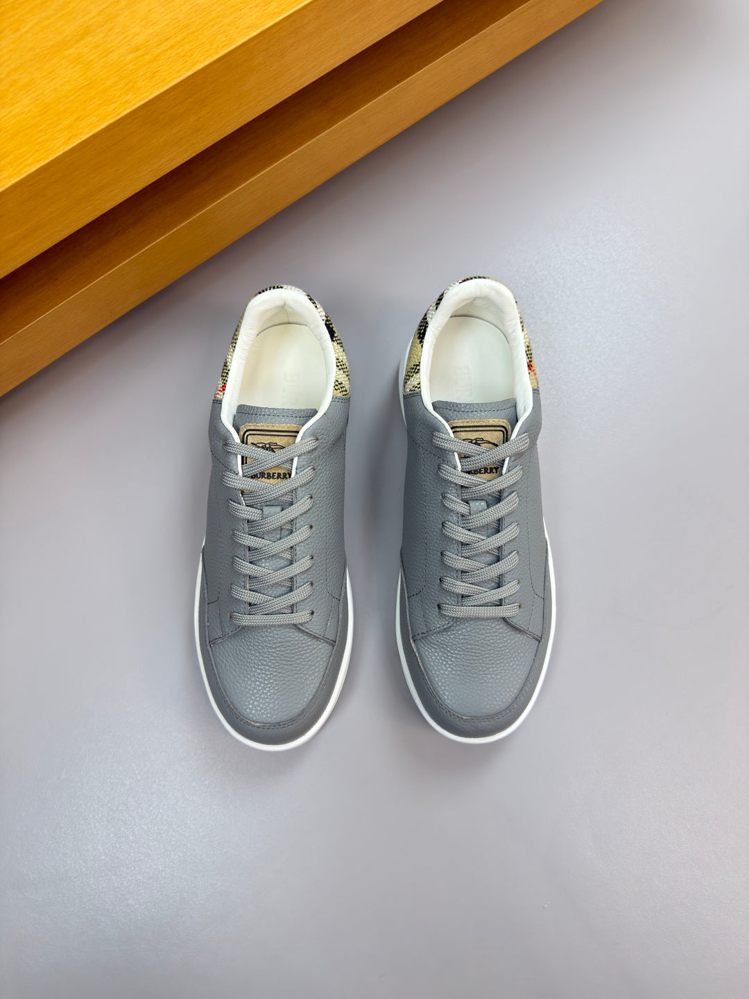 Pair of light gray lace-up sneakers with white midsoles and textured uppers