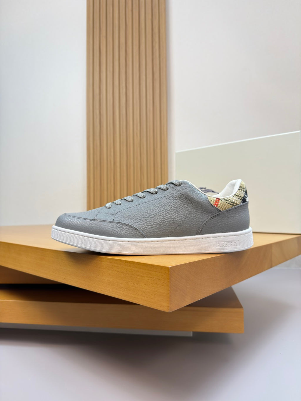 Light gray leather low-top sneakers with white sole and plaid heel detail