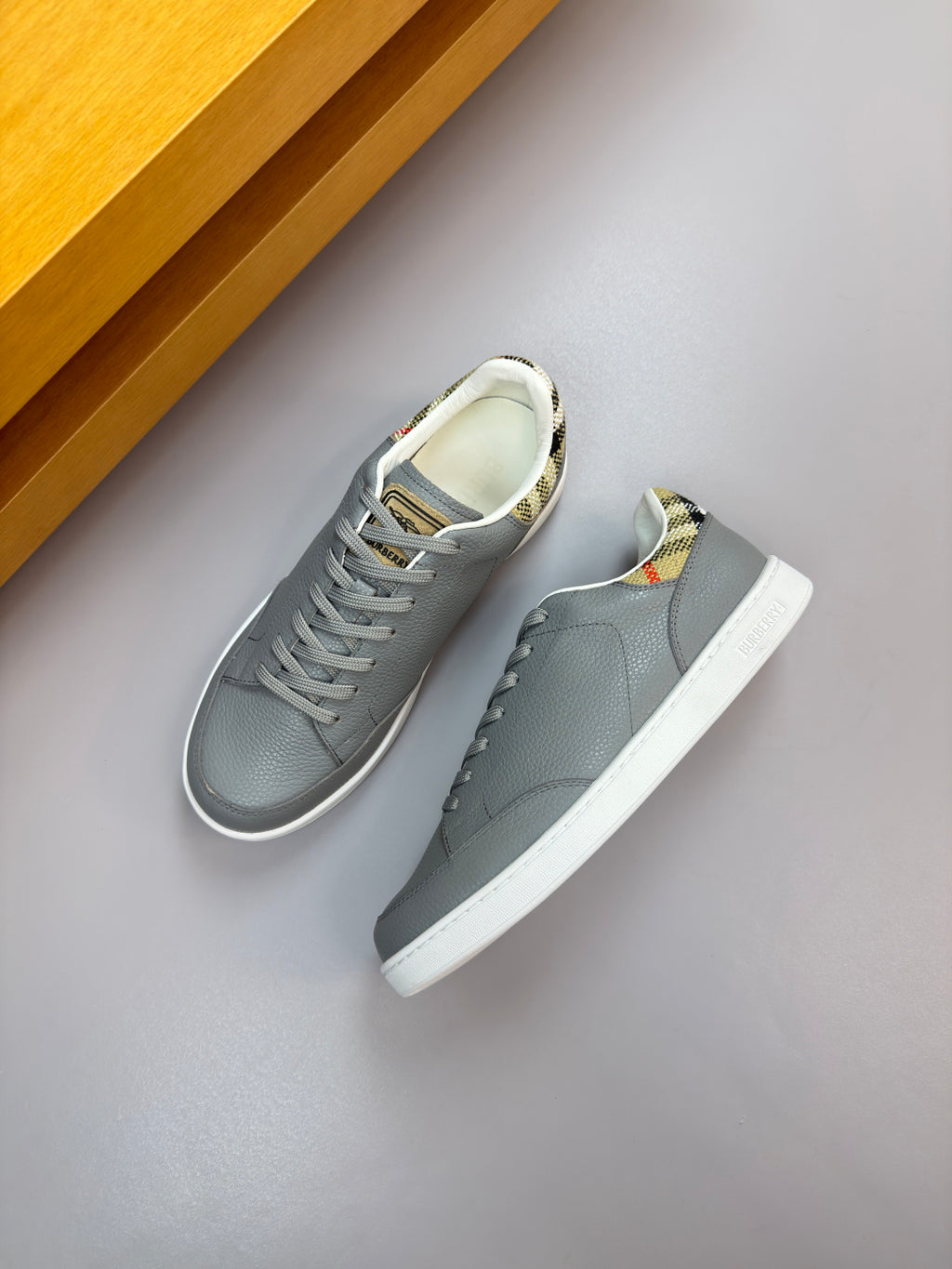 Light gray leather lace-up sneakers with white sole and multicolor logo tab