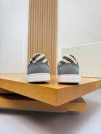 Light gray sneakers showing rounded toe and check-pattern heel patch