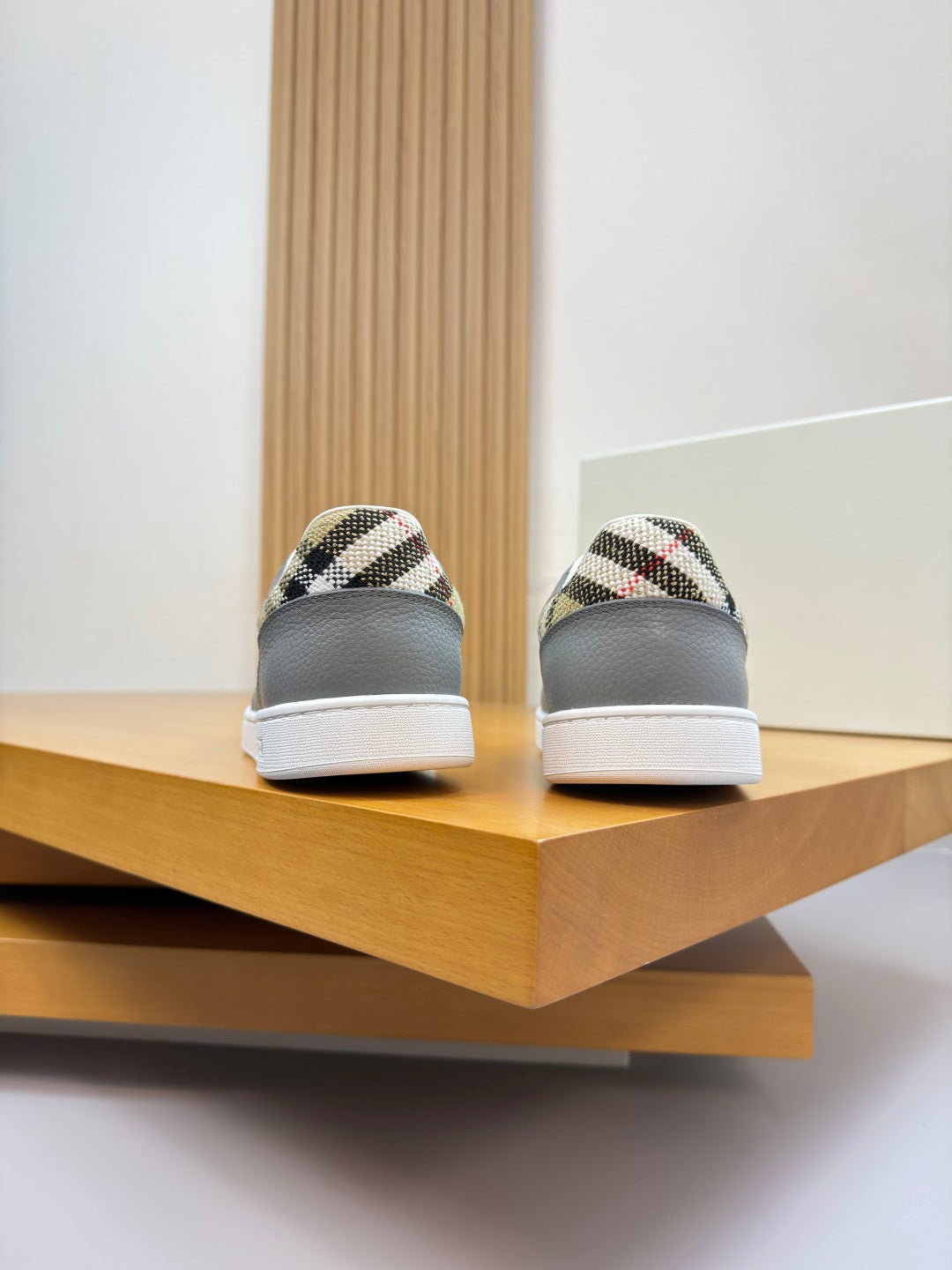 Light gray sneakers showing rounded toe and check-pattern heel patch