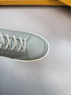Close-up gray leather sneaker toe with textured laces and white rubber edge