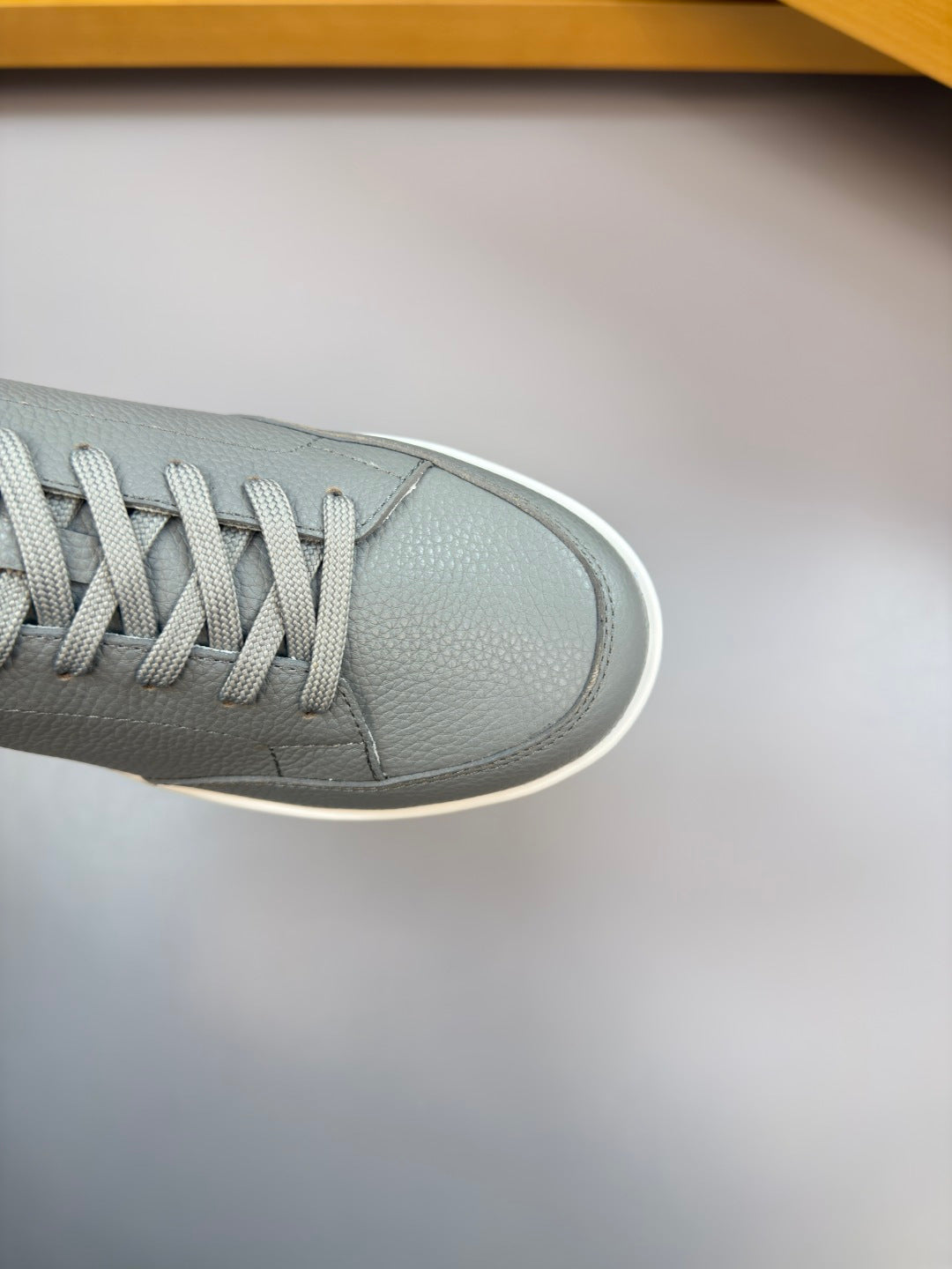 Close-up gray leather sneaker toe with textured laces and white rubber edge