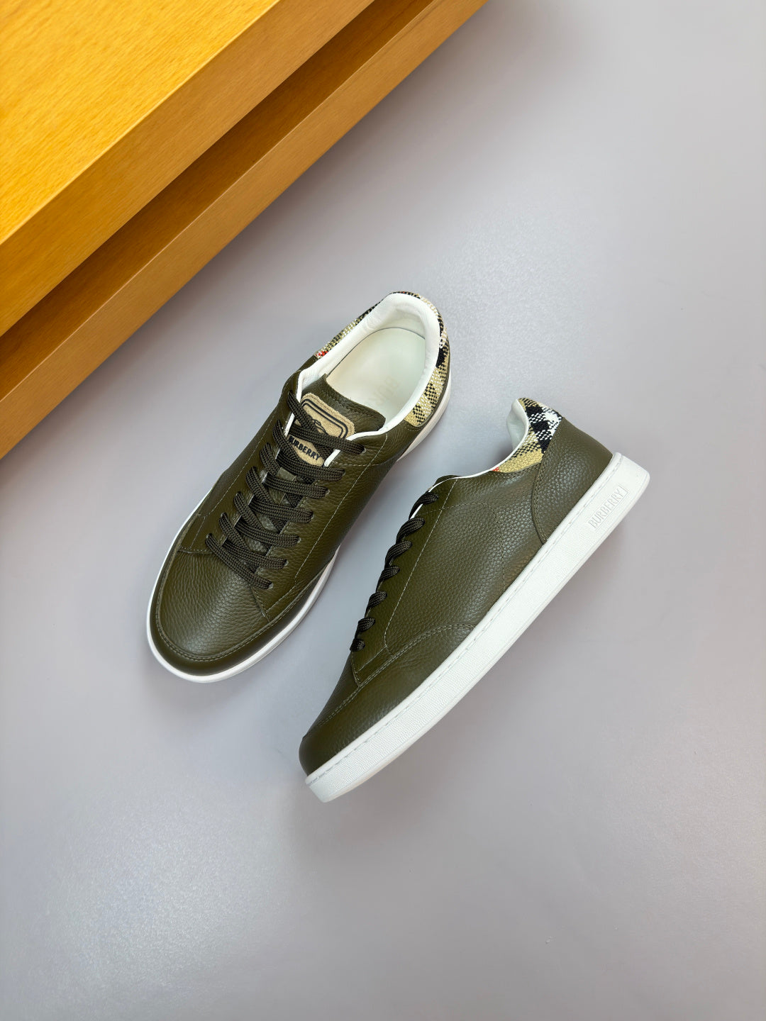 Pair of olive green leather lace-up sneakers with white soles and sidewall stitching