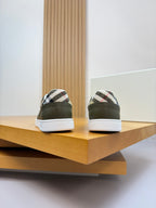 Olive green lace-up sneakers from the back with white soles and striped heel trim