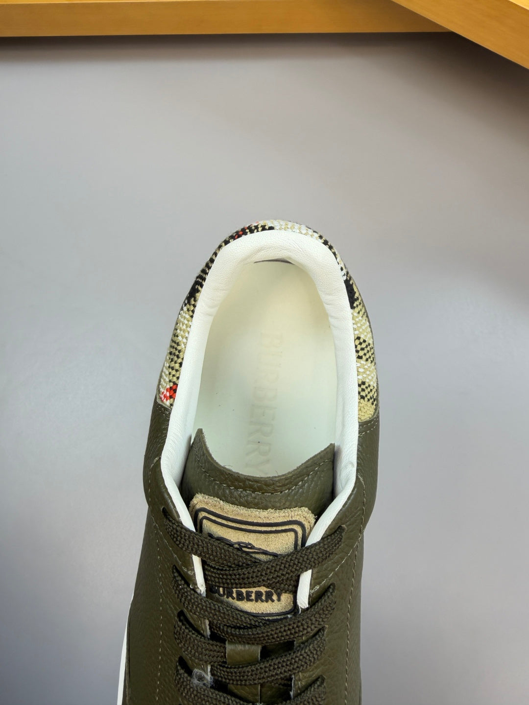 Olive green sneaker opening with Burberry logo on inner lining and patterned collar detail