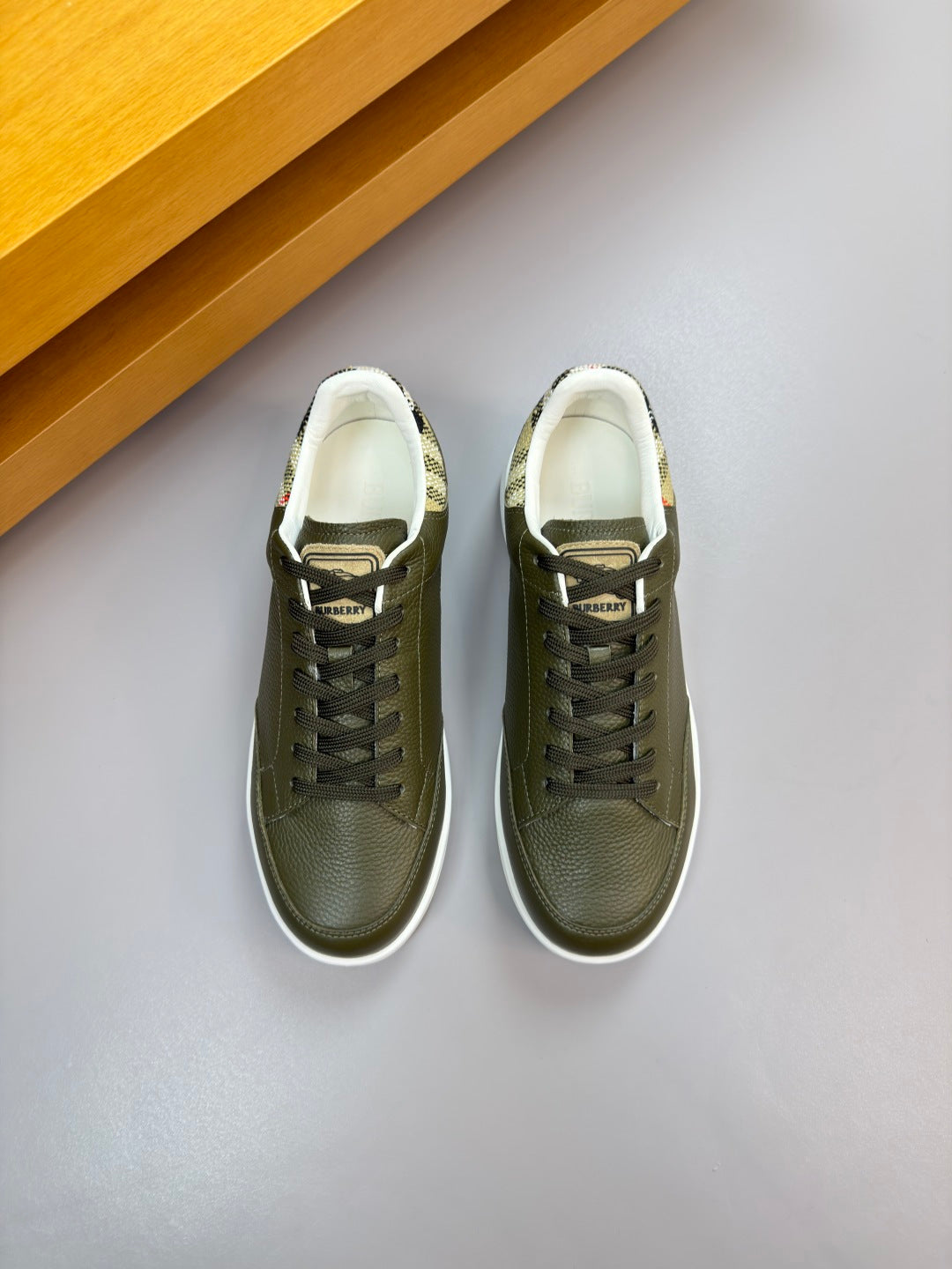 Olive green lace-up sneakers with white-trim collar and lightly textured leather upper