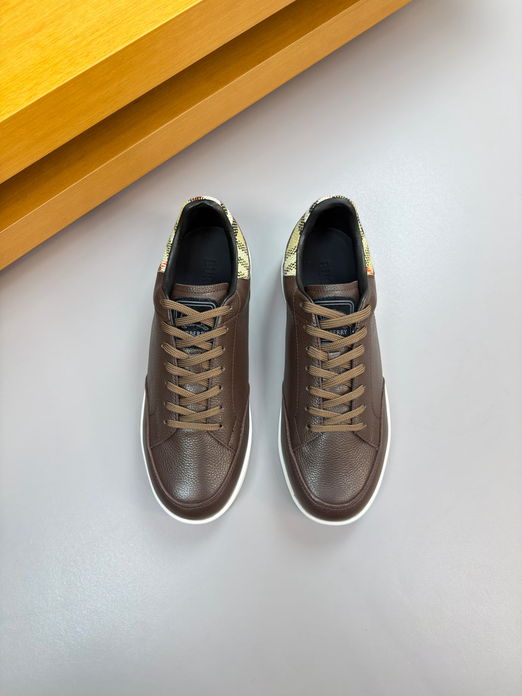 Brown lace-up sneakers with white midsoles and plaid lining at heel, pair view