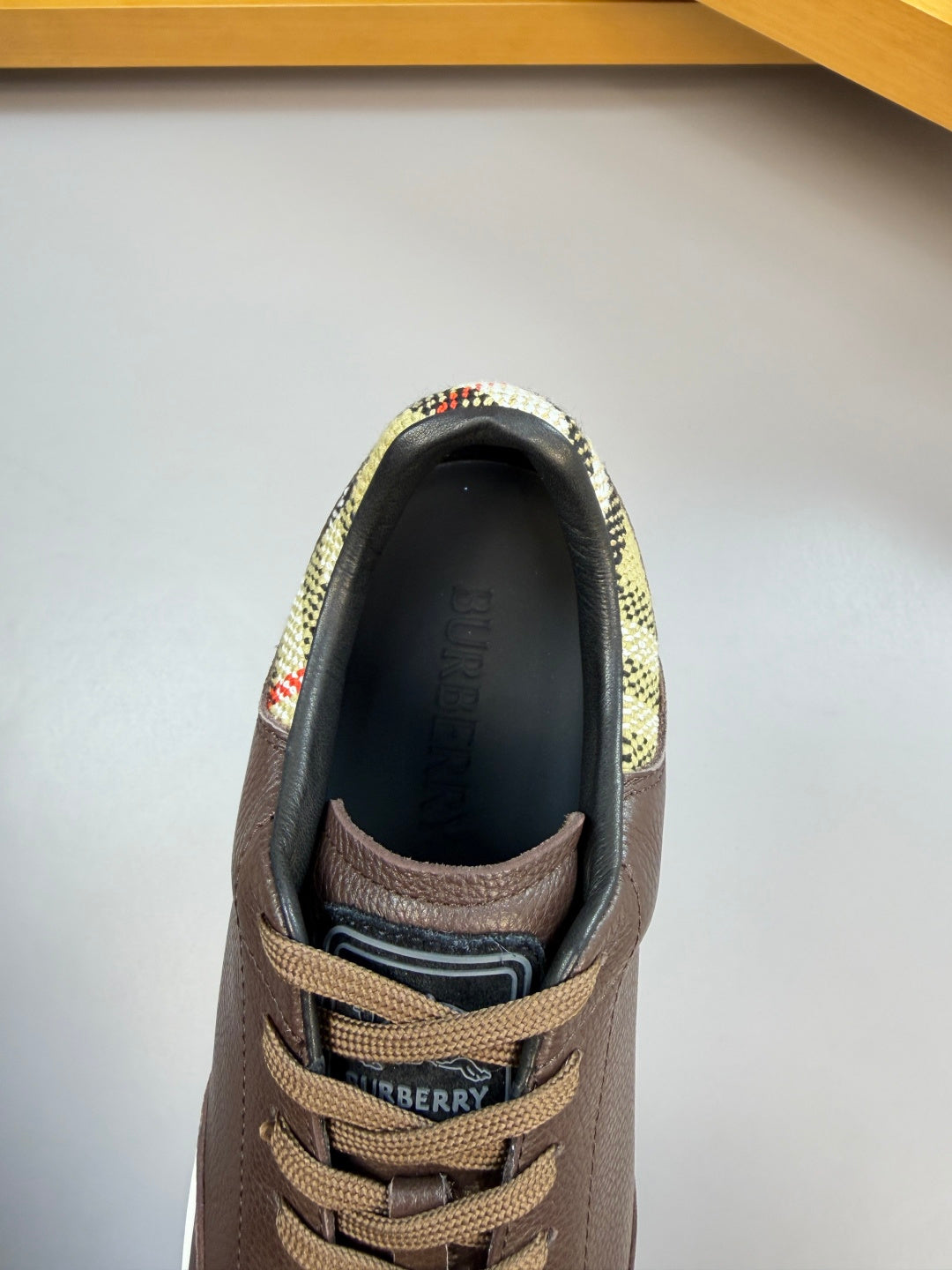 Brown sneaker interior with plaid lining at the collar and lace-up opening