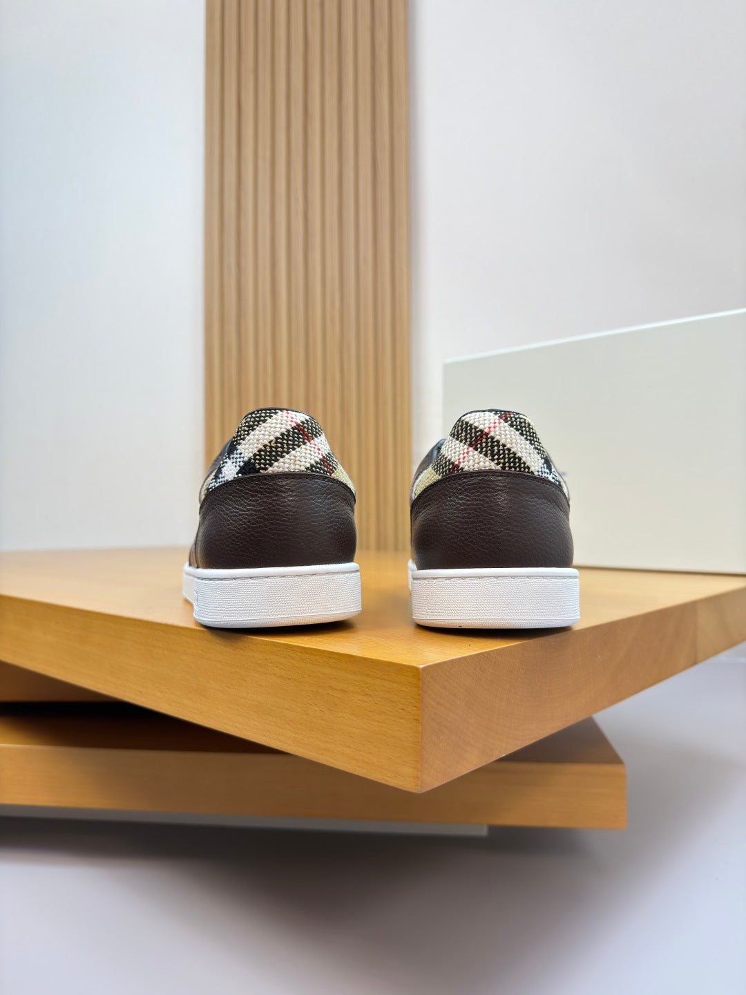 Back view of brown sneakers with plaid heel panel and white rubber soles
