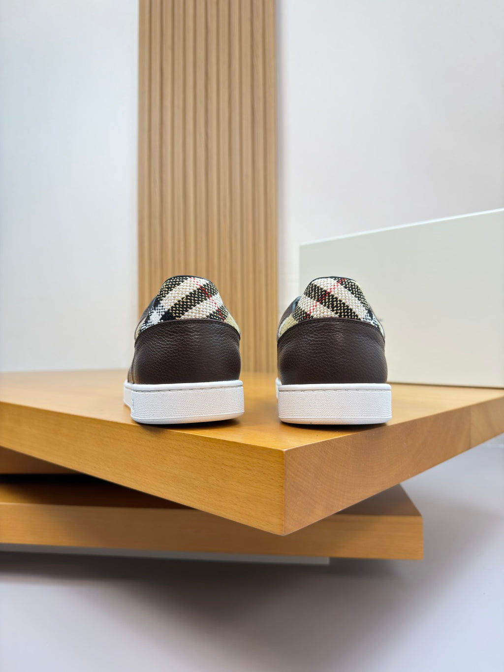 Brown sneakers with plaid heel panels and white rubber soles, back view pair