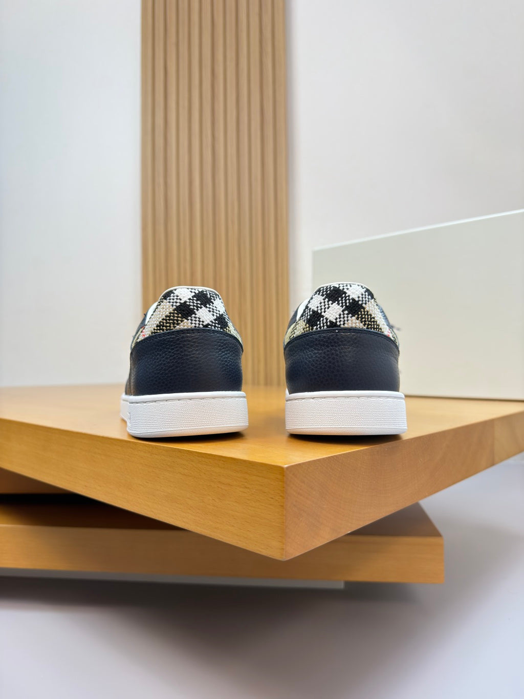 Back view of navy lace-up sneakers showing white midsoles and check-pattern heel panels