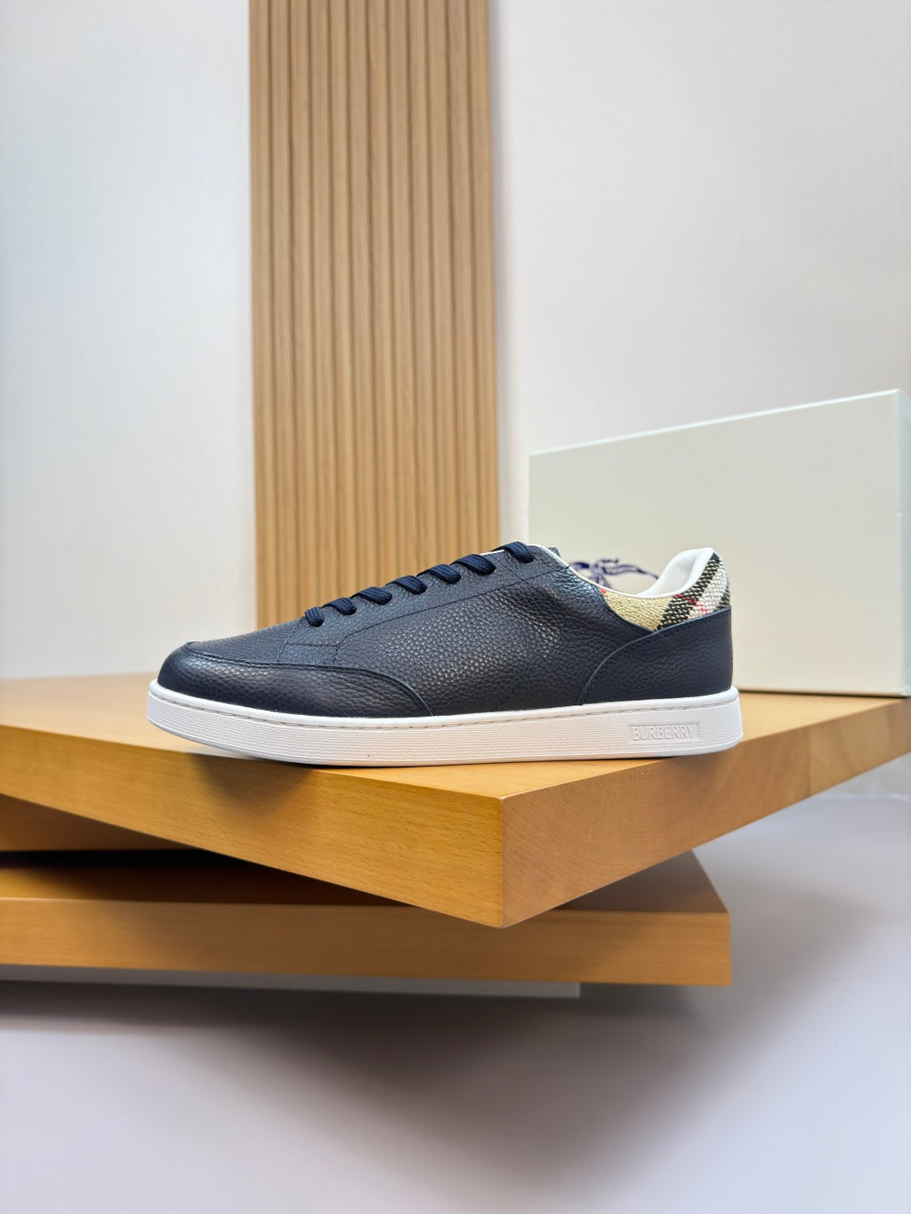 Navy low-top sneakers with white sole, lace-up front, and check-pattern heel collar