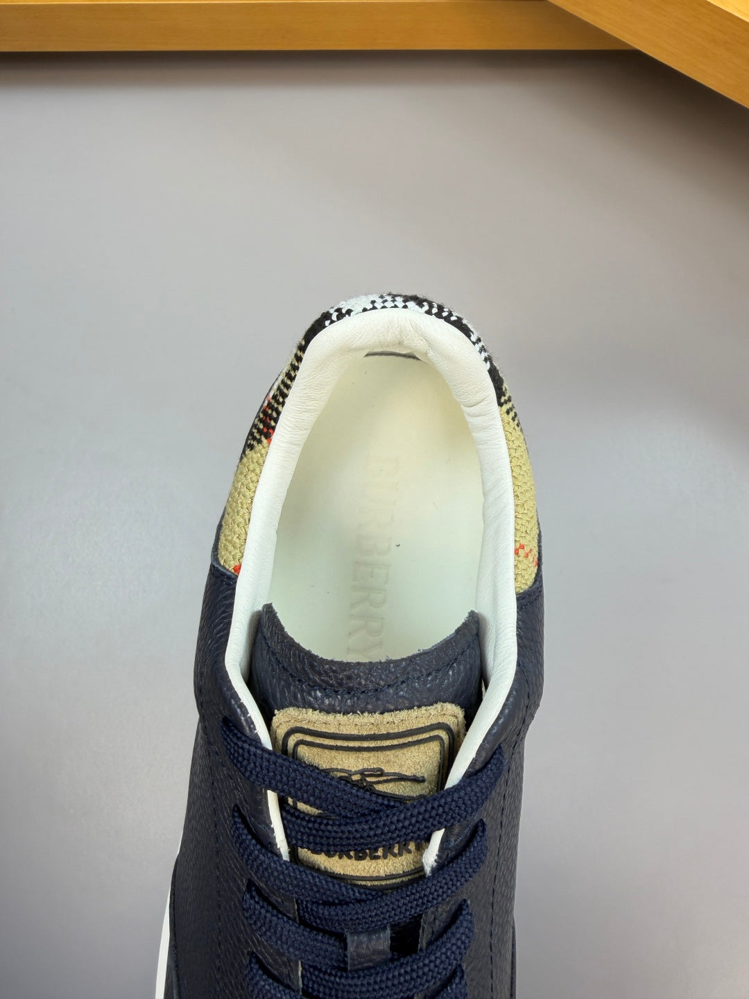 Navy sneaker with cream lining view, lace-up design and check-pattern collar