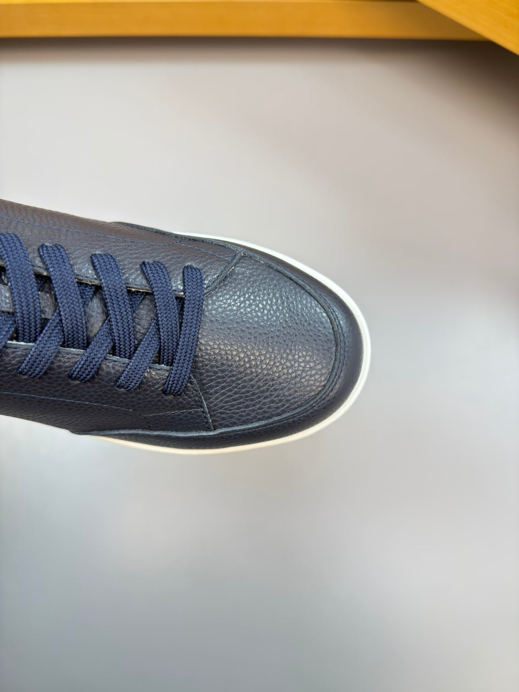 Close-up of a navy lace-up leather sneaker toe and side with textured finish