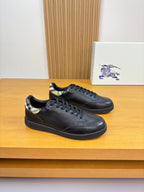 Black leather lace-up sneakers with Burberry check trim at heel and rubber sole.