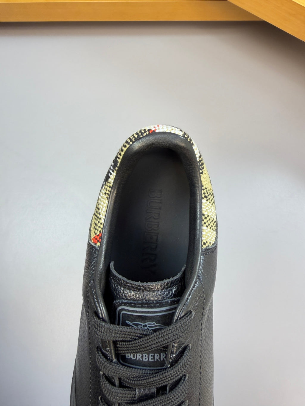 Black leather sneaker with Burberry-branded insole and check trim collar.