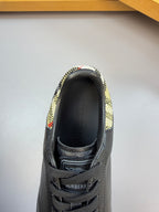 Heel and tongue of dark leather low-top sneaker with patterned collar and branding