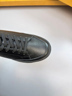 Side view of dark leather low-top sneaker with black laces and textured toe panel