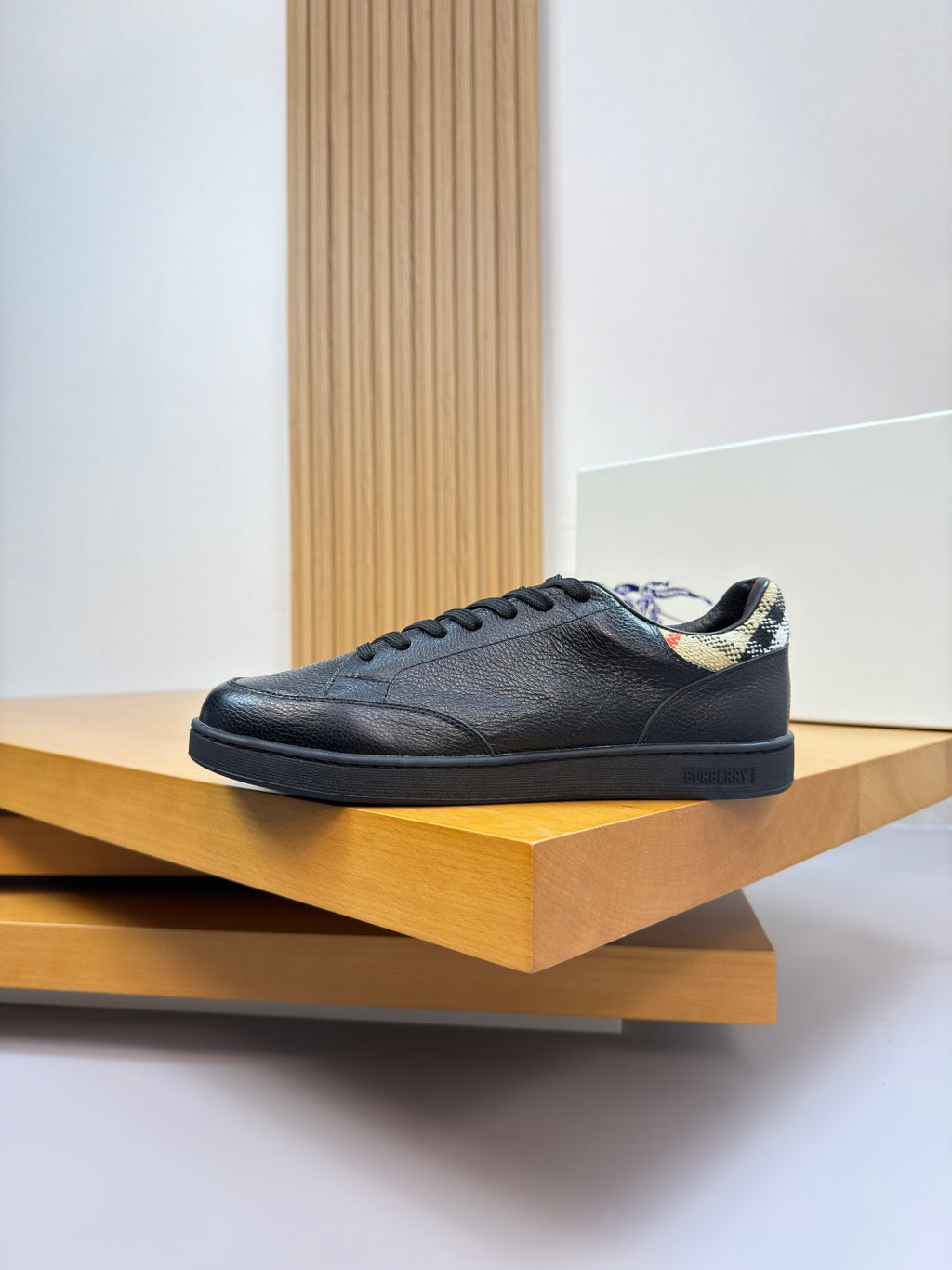 Single dark leather low-top sneaker on a shelf with patterned inner collar