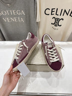 Maroon suede sneakers with white laces, shown in hand, beige sole.