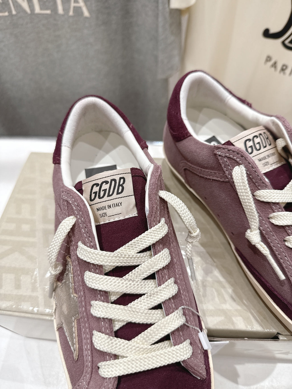 Maroon suede sneaker with white laces and GGDB label on tongue, close-up.